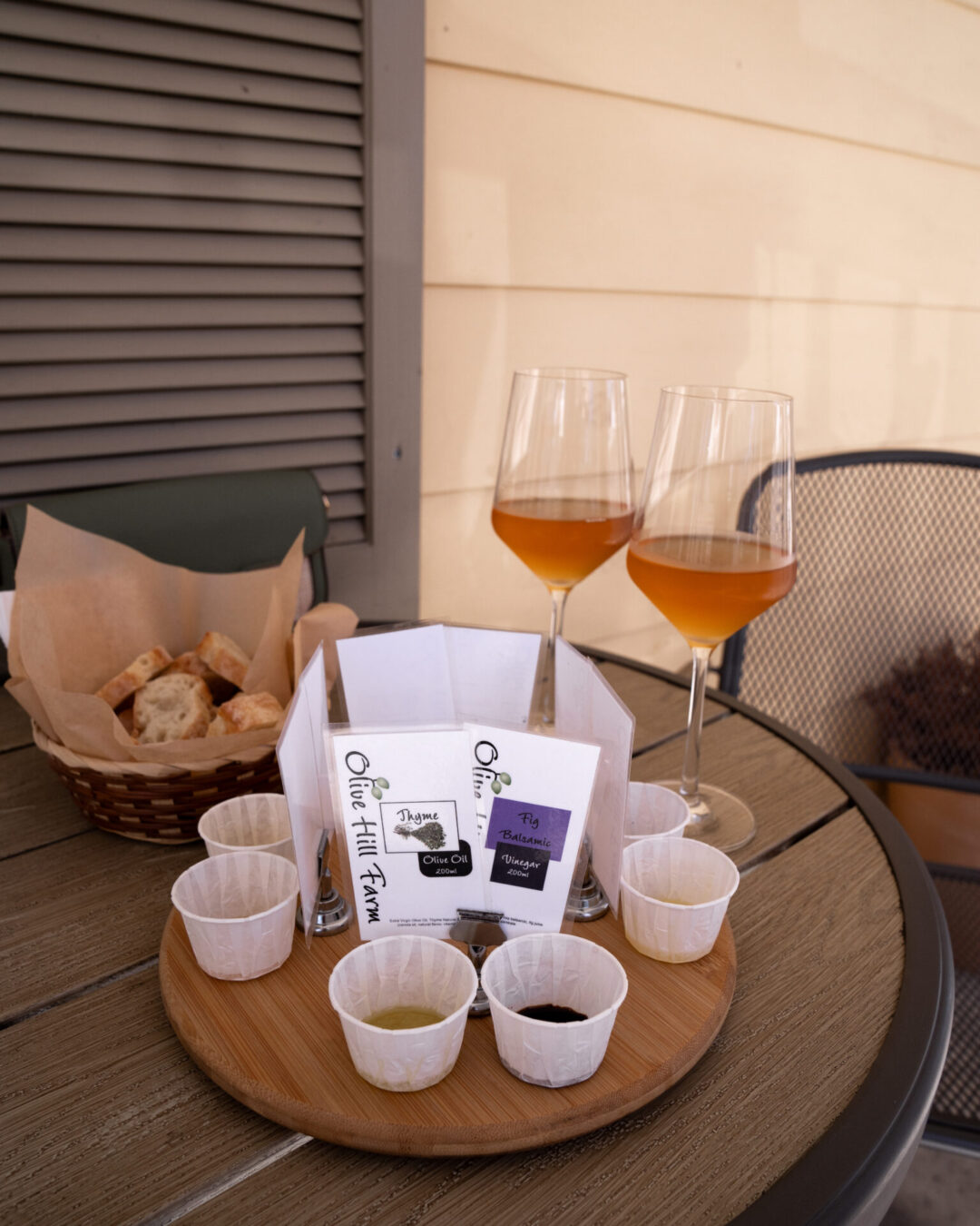 Two glasses of orange wine and a tray of olive oil samples and bread at Olive Hill Farm in Los Olivos, California