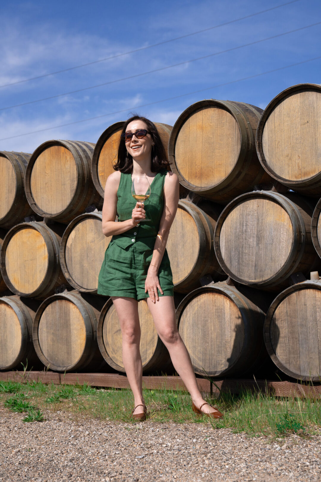 Travel Blogger Jordan Gassner smiling in front of a wall of wooden wine barrels at Chamisal Vineyards near San Luis Obispo, California