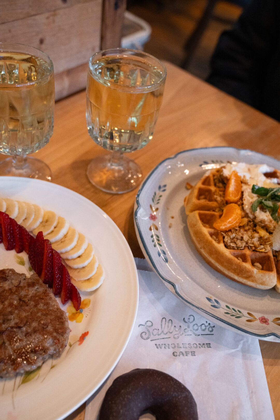 San Luis Obispo Travel Guide: A Belgian waffle, chocolate donut and plate of sausages and fruit from Sally Loo's Wholesome Cafe