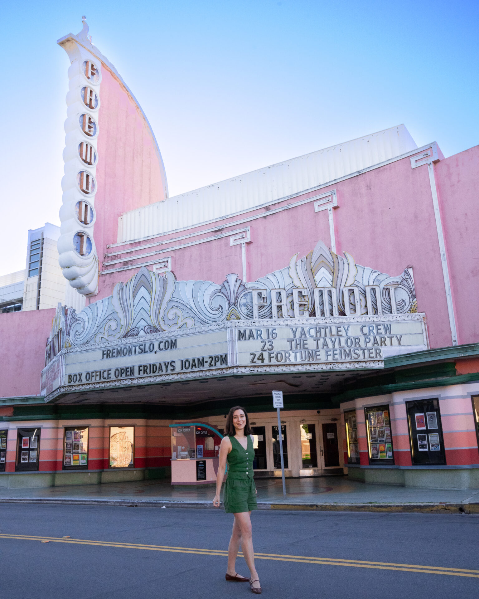 Travel Blogger Jordan Gassner smiling in front of the pink Fremont Theater in Downtown San Luis Obispo, California