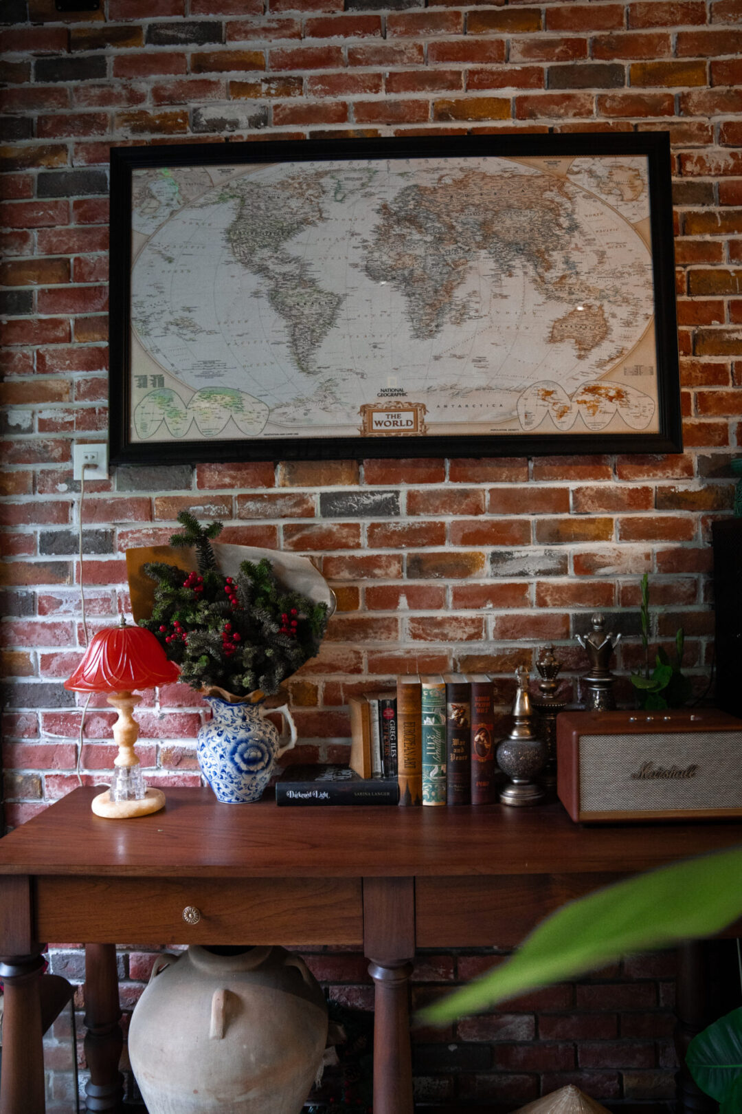 A table with a selection of books and a record player below a world map inside the Chum Boutique Hotel Lobby in Hue, Vietnam 