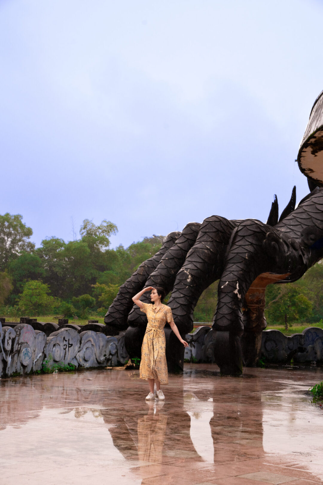 Travel Blogger Jordan Gassner looking out over the lake at Ho Thuy Thien Abandoned Waterpark, a giant man-made "Dragon's claw" right behind her