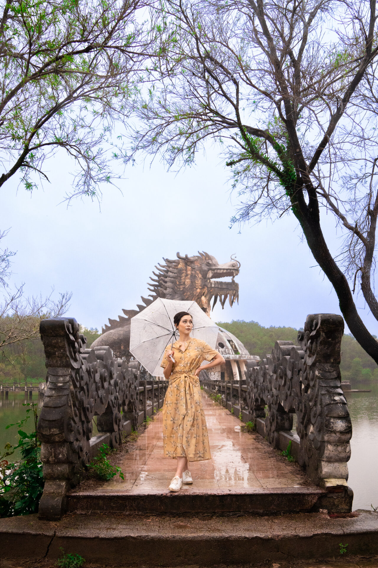 Travel Blogger Jordan Gassner standing with her hand on her hip while on a pathway leading up to a dragon structure at Ho Thuy Tien Abandoned Waterpark in Hue, Vietnam