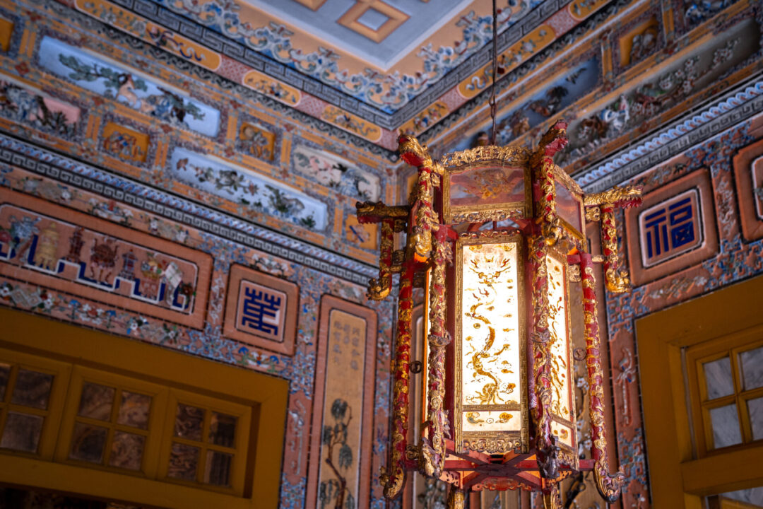 An intricately decorated lantern with red and gold design hanging inside the lavish Tomb of Khai Dinh in Hue, Vietnam