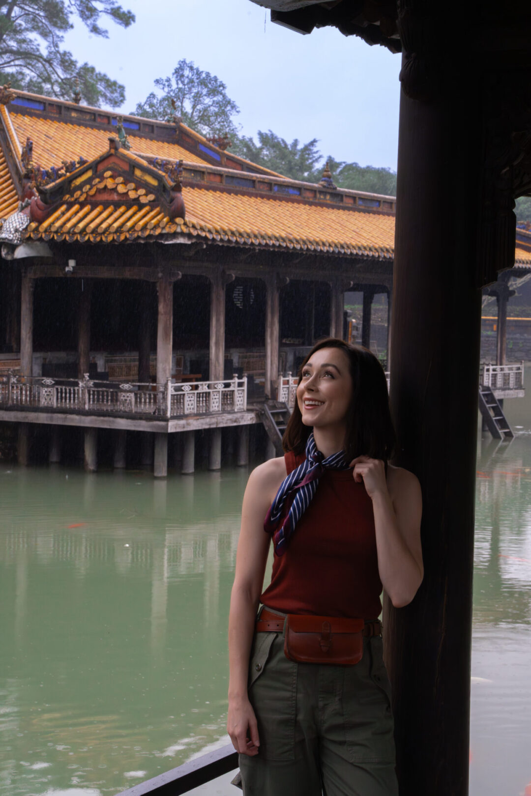 Travel Blogger Jordan Gassner leaning against a column in an adventure-inspired outfit near the lake inside the Tomb of Tu Duc in Hue, Vietnam