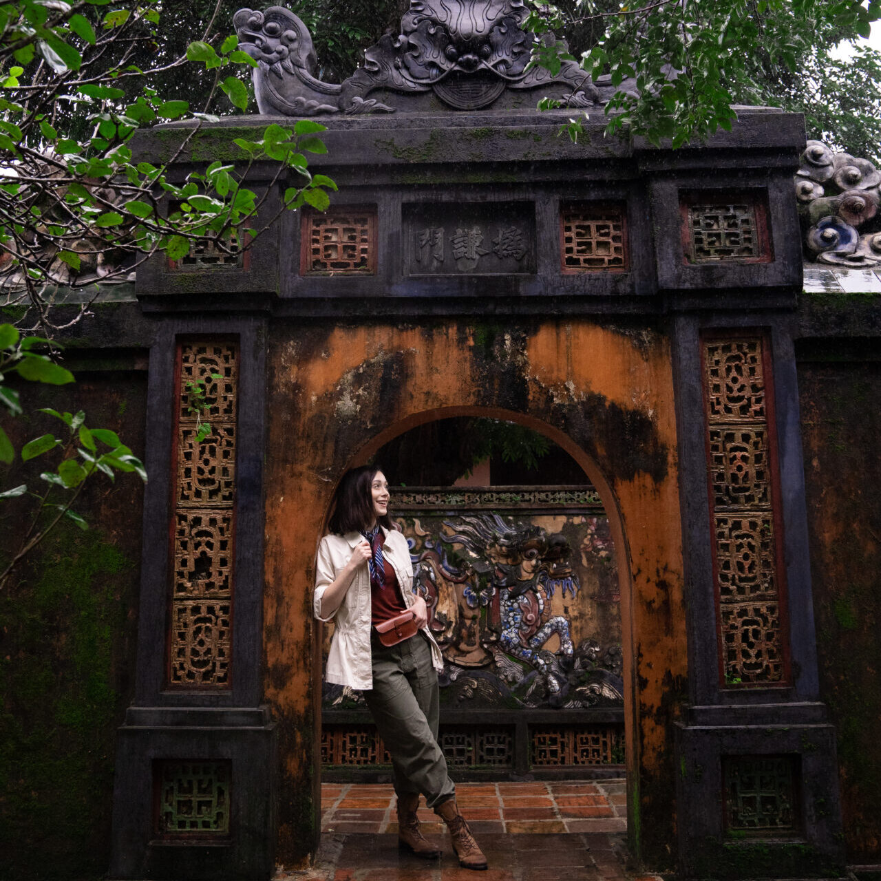 Travel Blogger Jordan Gassner leaning against an orange and black archway and smiling inside the Tomb of Tu Duc in Hue, Vietnam