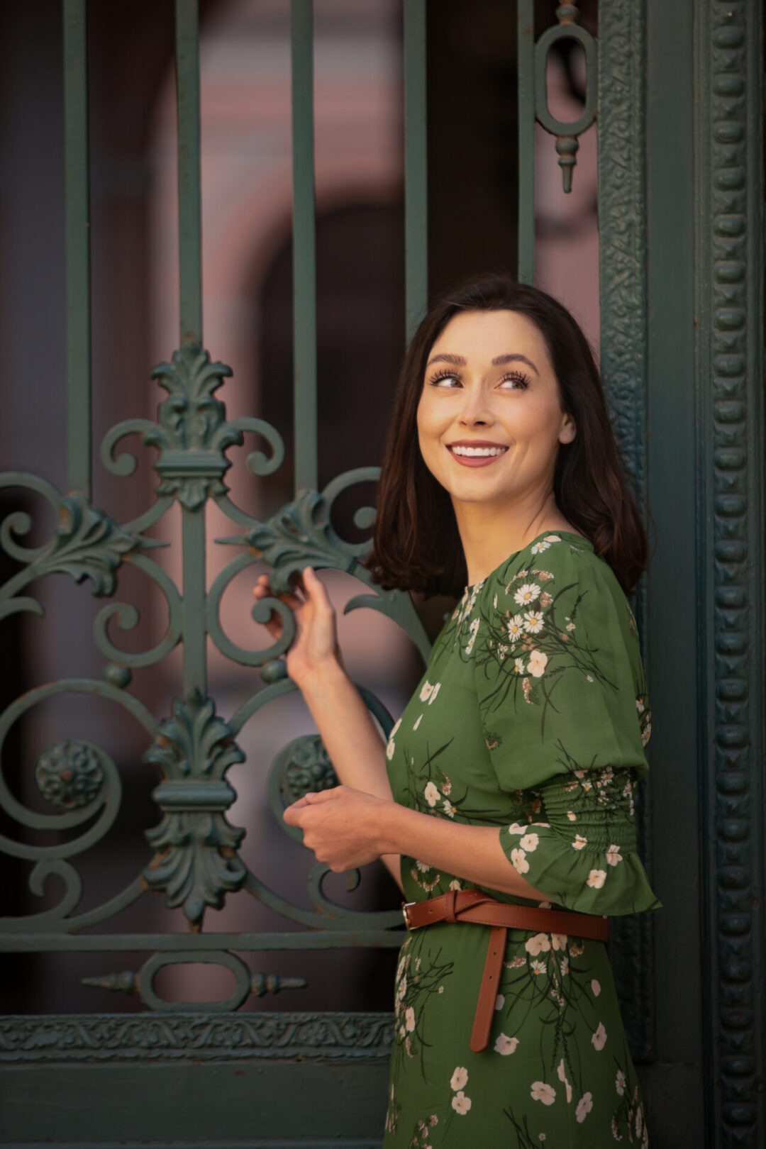 Travel Blogger Jordan Gassner holding onto a green, metal gate and looking over her shoulder smiling in Lima, Peru