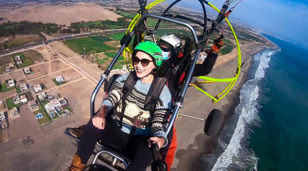 Travel Blogger Jordan Gassner smiling while paragliding over the coastline of Peru