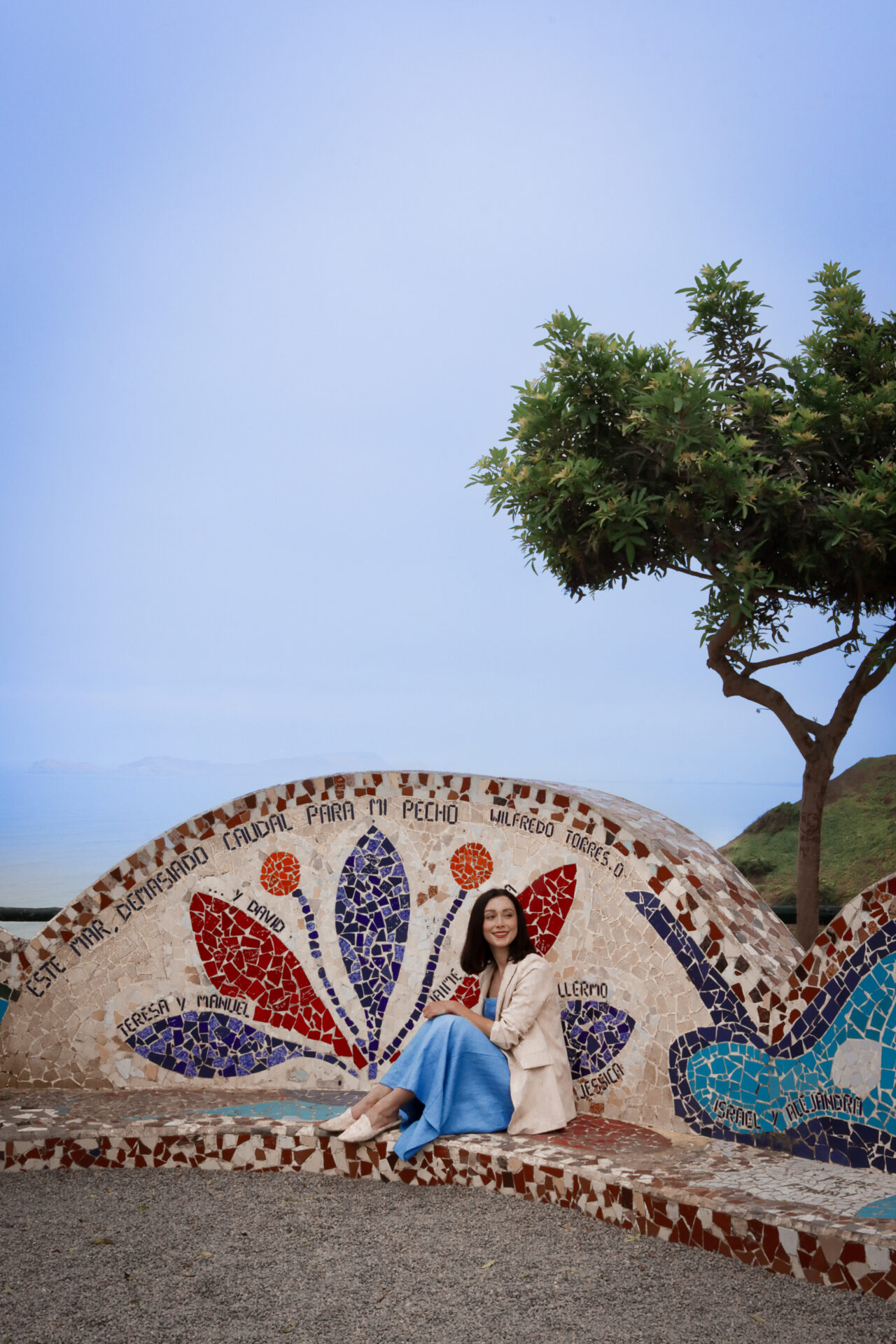 Travel Blogger Jordan Gassner sitting on a colorful mosaic-decorated bench in Pareque del Amor in Lima, Peru 