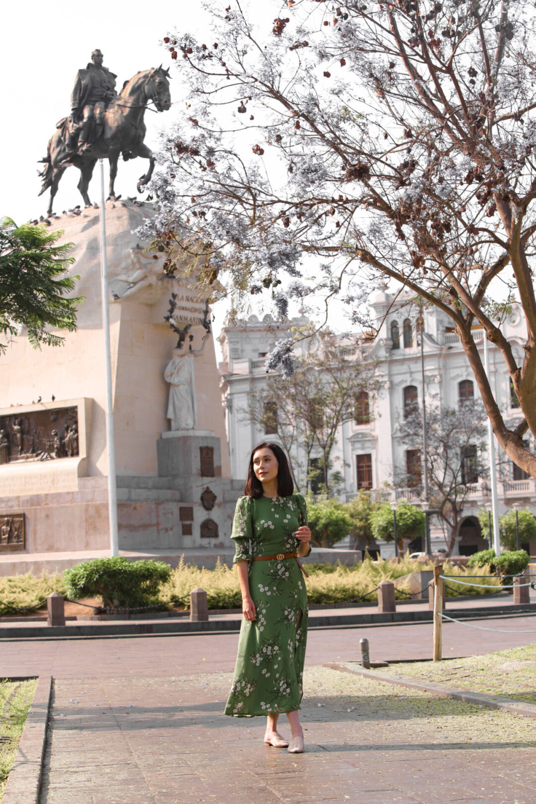 Travel Blogger Jordan Gassner walking along a pathway in between the green grass patches and trees in Lima's Plaza San Martin