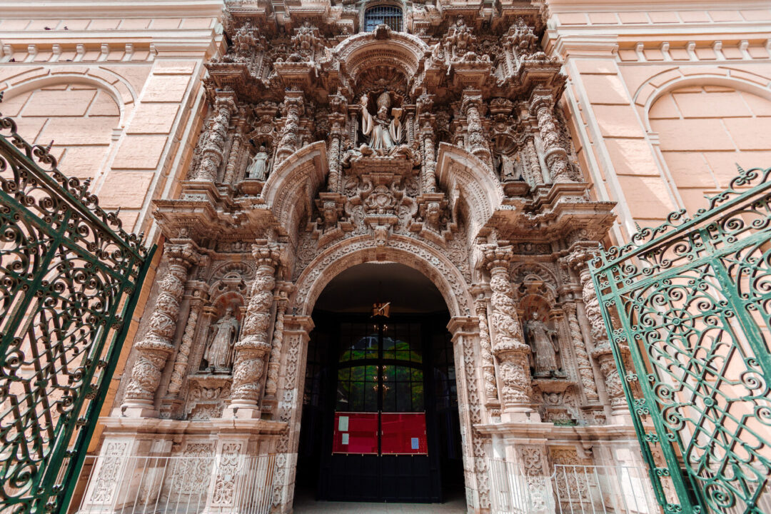 Must See In Lima: A green gate below the stone-carved entrance of the San Agustín Church in Lima, Peru