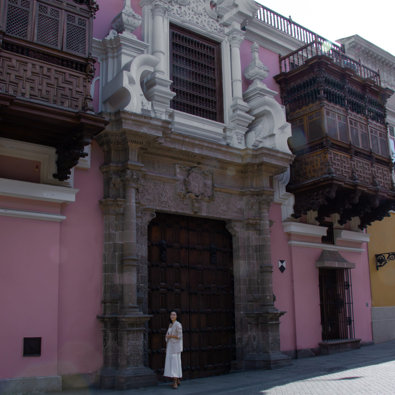 Travel Blogger Jordan Gassner standing outside the pink facade of Torre Tagle in Lima, Peru