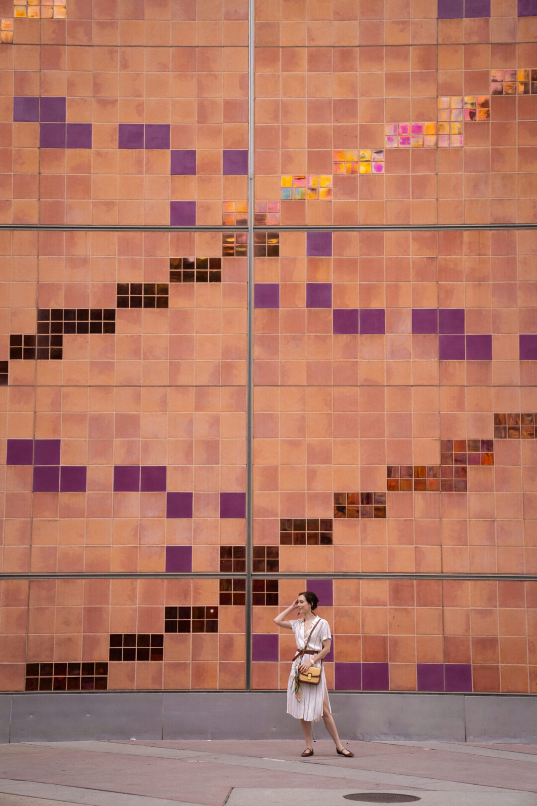 LA Museums: Travel Blogger Jordan Gassner standing and smiling in front of a purple, red and orange tiled wall at the California Science Center