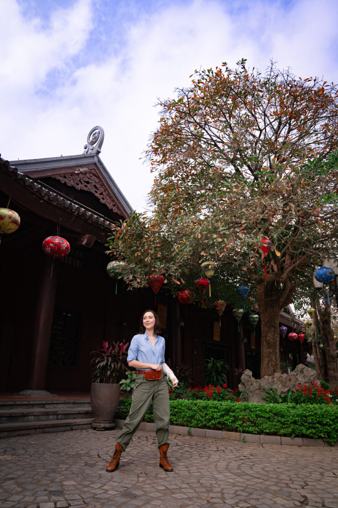Travel Blogger Jordan Gassner standing in front of one of the visitor center buildings, decorated with colorful lanterns, in Trang An, Vietnam