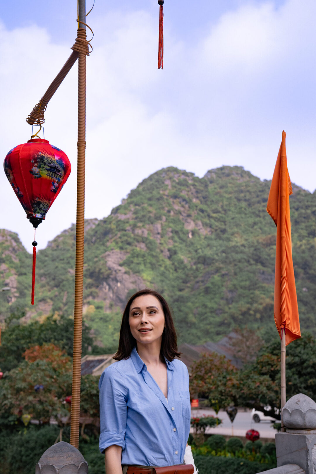 Travel Blogger Jordan Gassner standing and smiling on a bridge decorated with colorful lanterns in Ninh Binh, Vietnam