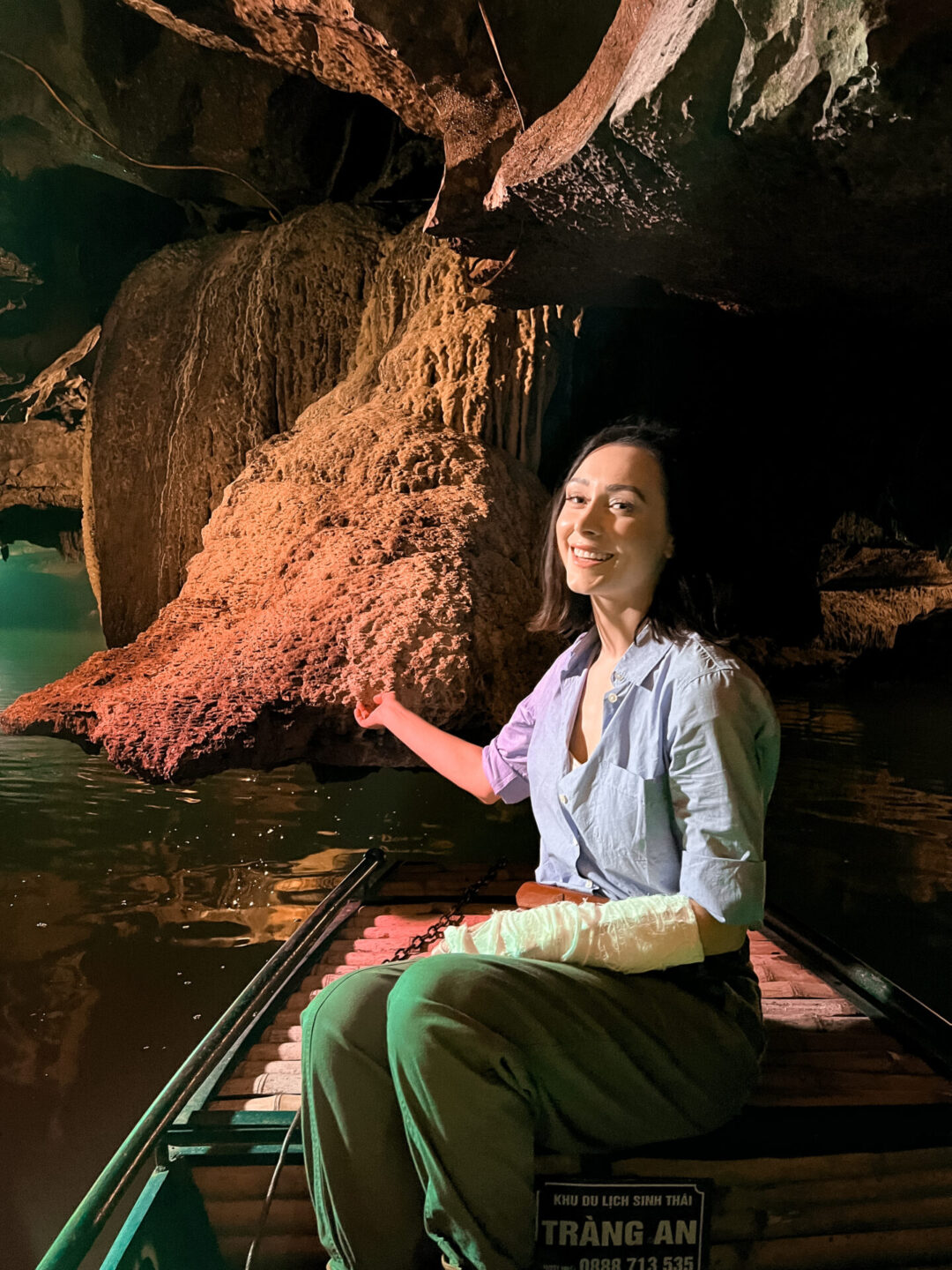 Travel Blogger Jordan Gassner smiling from a sampan boat inside a cave at Trang An, Vietnam