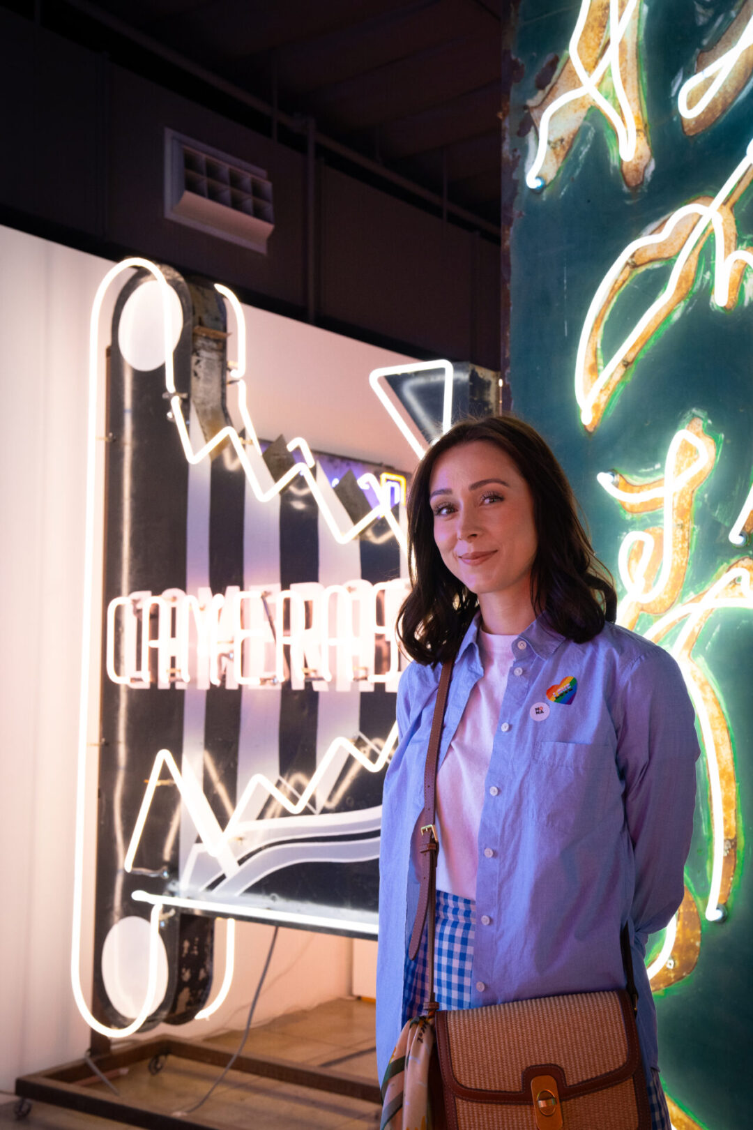 Travel Blogger Jordan Gassner smiling in front of a few neon signs inside the Museum of Neon Art in Los Angeles, California