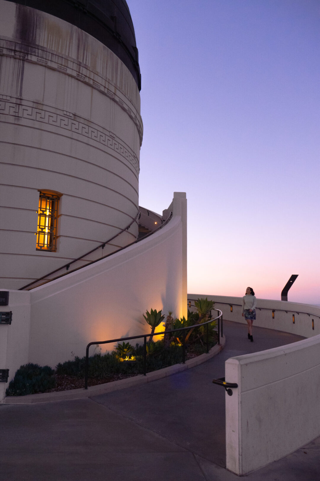 Travel Blogger Jordan Gassner walking down the ramp at Griffith Observatory during a purple sunset hour in Los Angeles, California