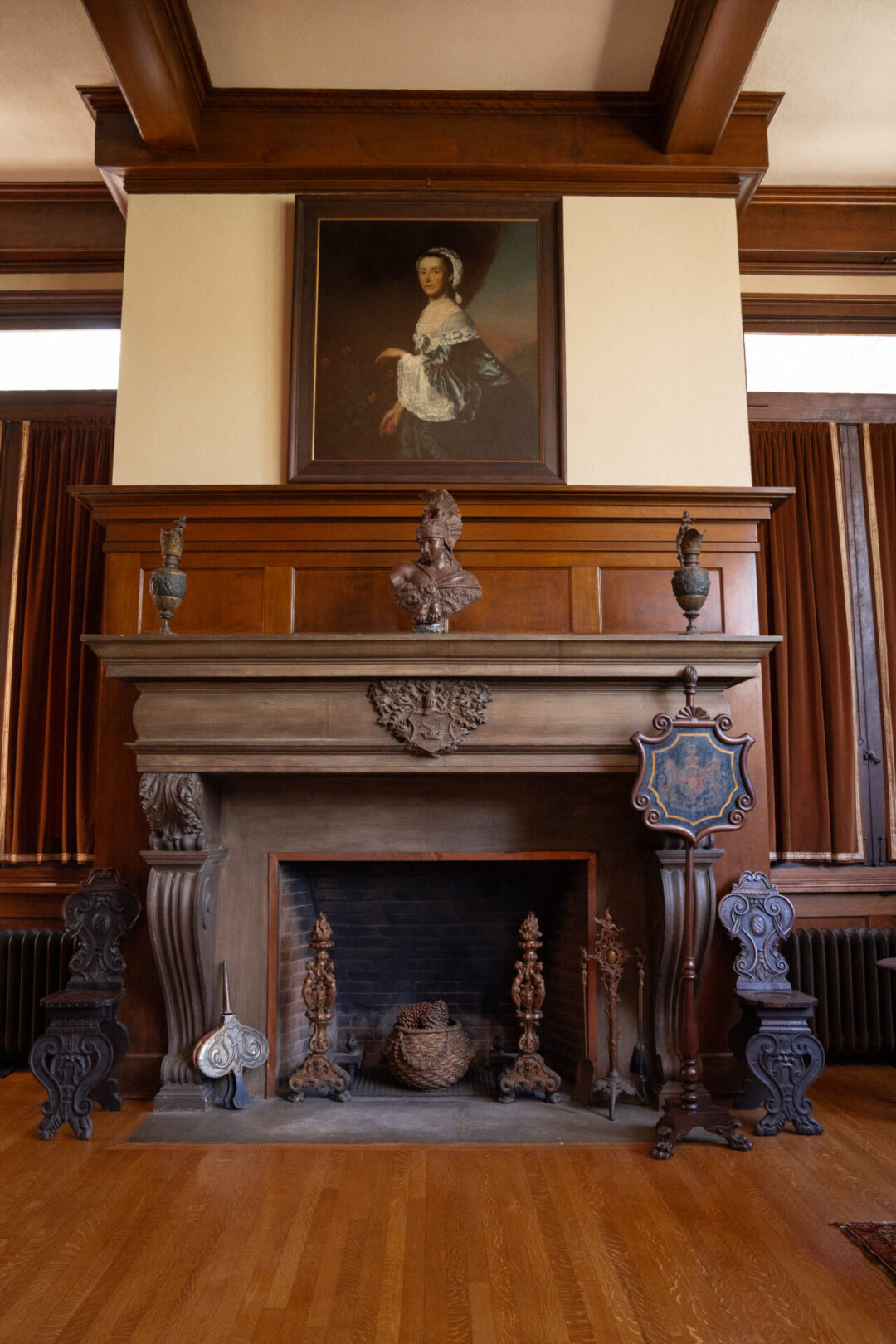 A large wood fireplace and classic portrait inside the Fenyes Mansion in Pasadena, California
