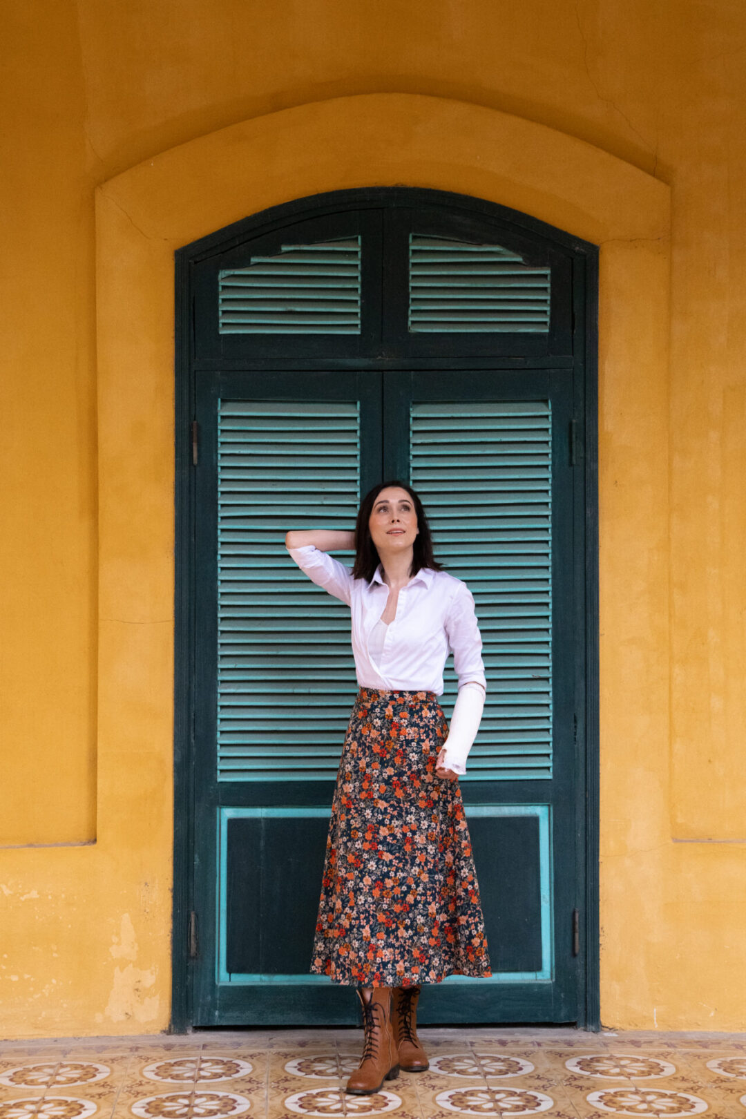 Travel Blogger Jordan Gassner standing in front of a green door set in a yellow building in Hanoi, Vietnam