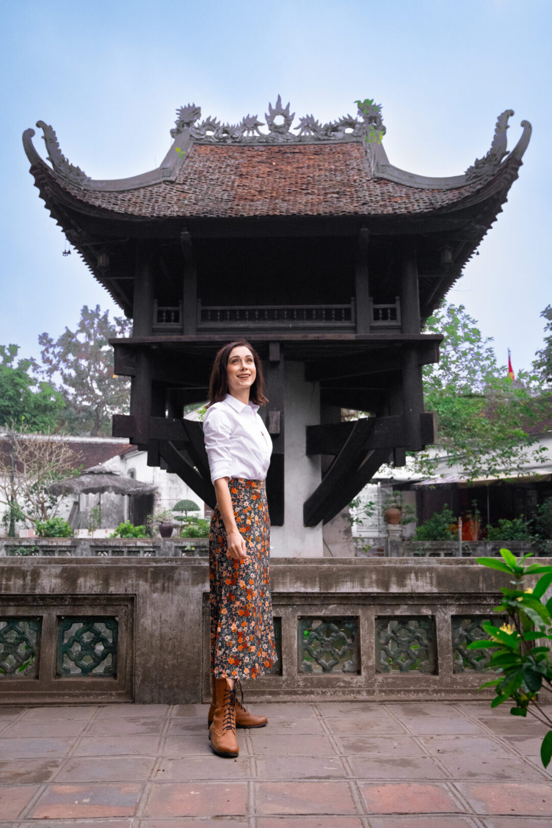 Travel Blogger standing and smiling along the back side of One Pillar Pagoda in Hanoi, Vietnam