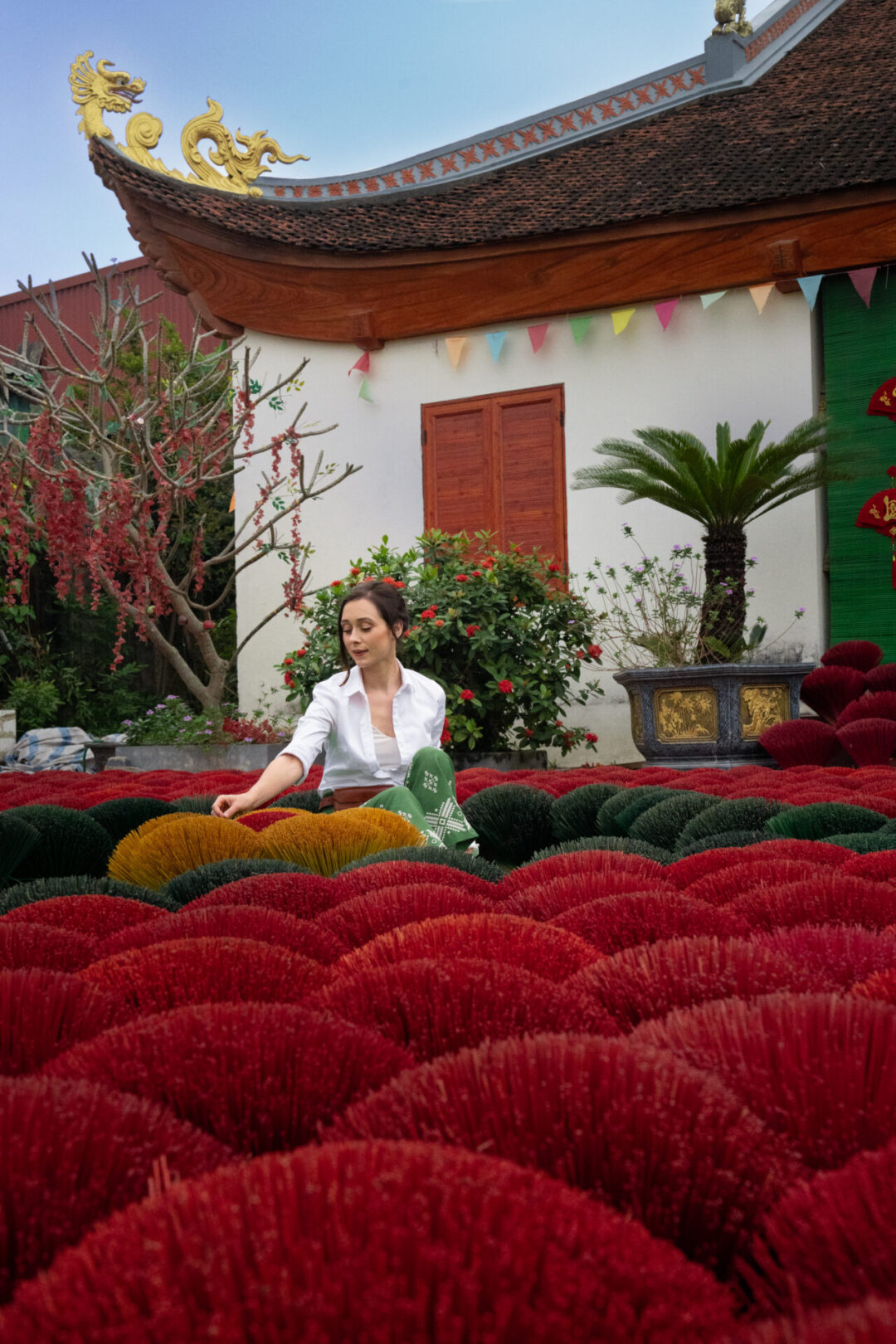 Travel Blogger Jordan Gassner sitting amongst colorful incense bundles in the village of Quang Phu Cau near Hanoi, Vietnam