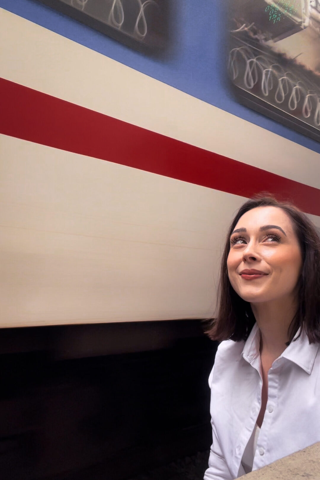 Travel Blogger Jordan Gassner smiling while a train passes closely behind her from Hanoi's Instagram-famous Train Street