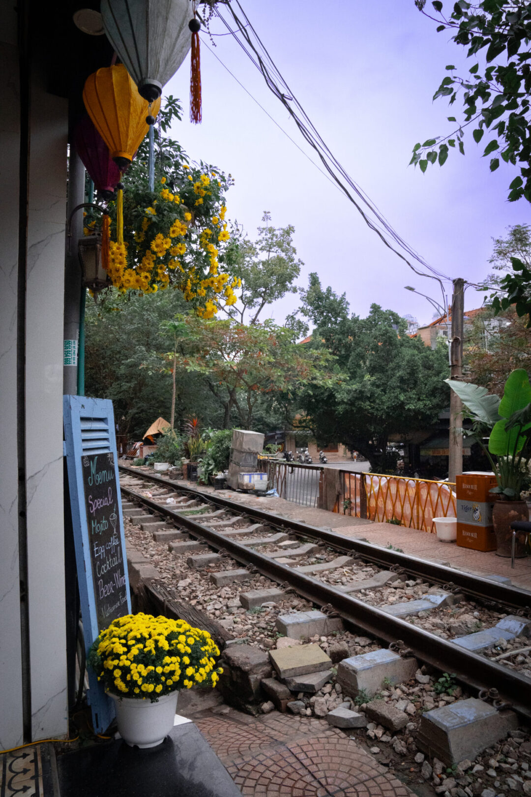 A blue sign and a flower pot sitting at the entrance of a cafe along Train Street in Hanoi, Vietnam