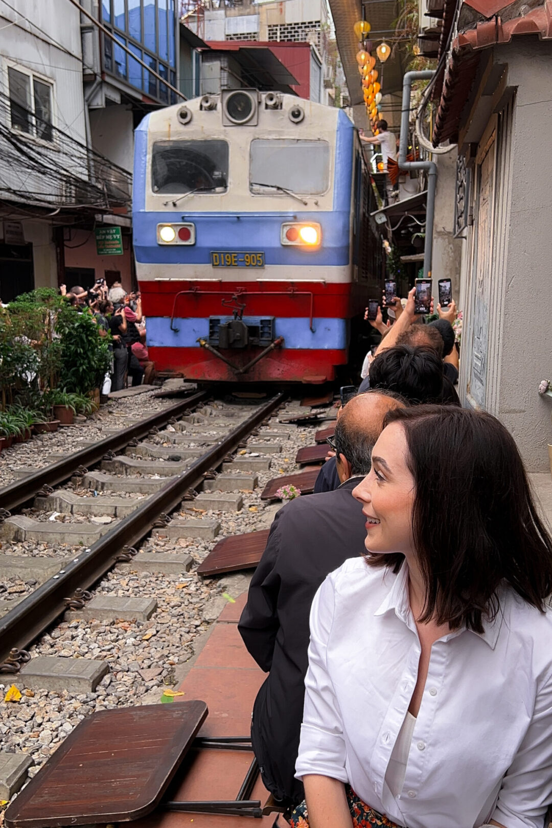 Travel Blogger Jordan Gassner smiling and looking toward an approaching train on Hanoi's Instagram-famous Train Street