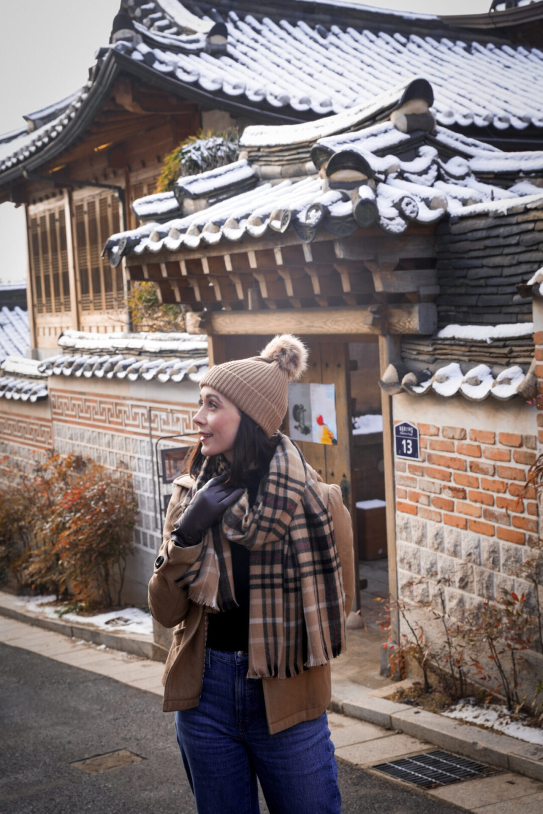 Travel Blogger Jordan Gassner bundled up and smiling near a traditional hanok house inside Bukchon Hanok Village in Seoul, South Korea