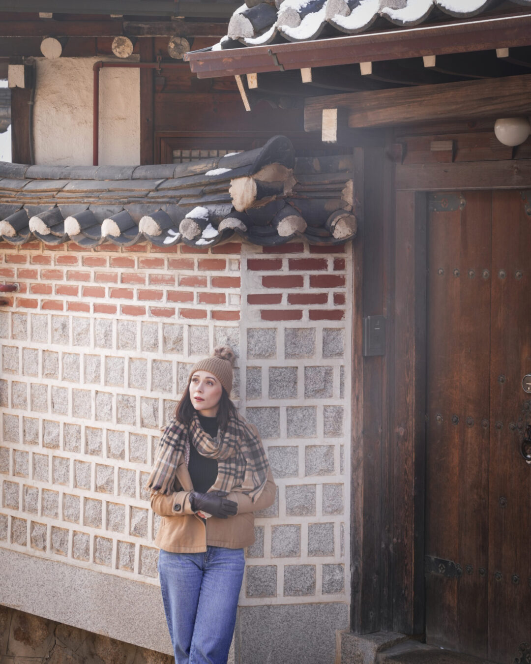 Travel Blogger Jordan Gassner looking up while against a wall outside a traditional hanok house in Bukchon Hanok Village in Seoul, South Korea