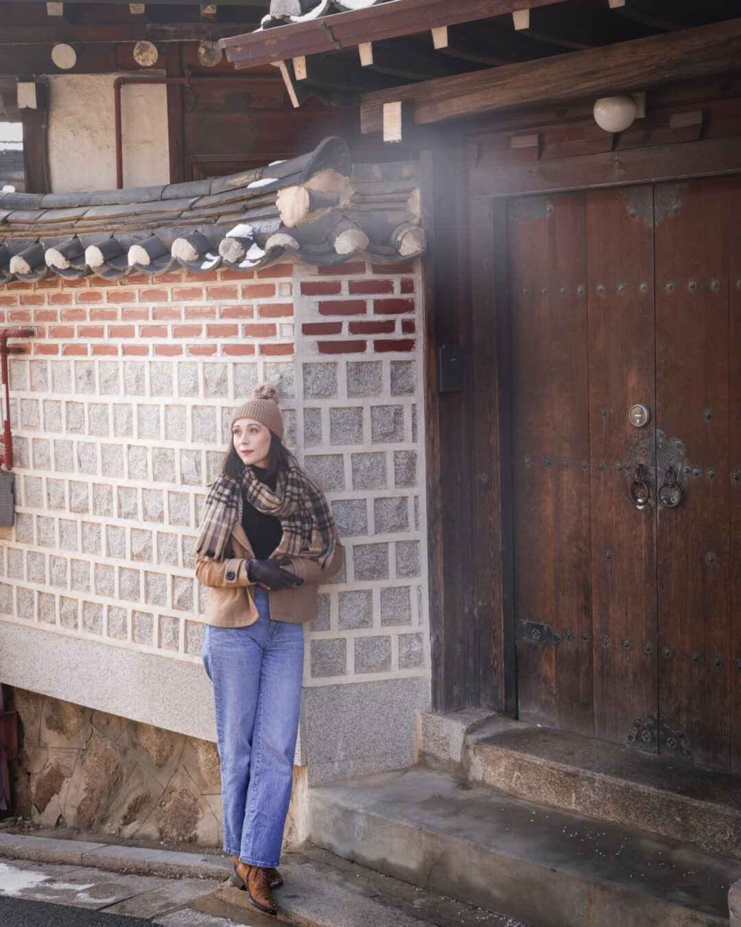 Travel Blogger Jordan Gassner smiling near a wall outside a traditional hanok house in Bukchon Hanok Village in Seoul, South Korea
