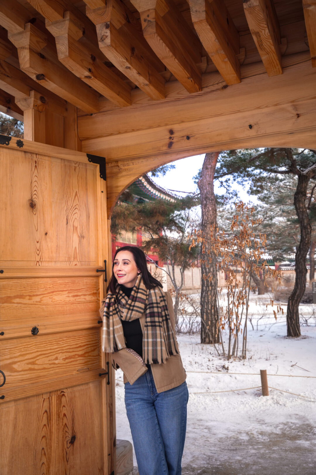 Travel Blogger Jordan Gassner smiling while leaning against a gate in between Geonchunmun Gate and Gyejodang Hall inside Gyeongbokgung Palace in Seoul
