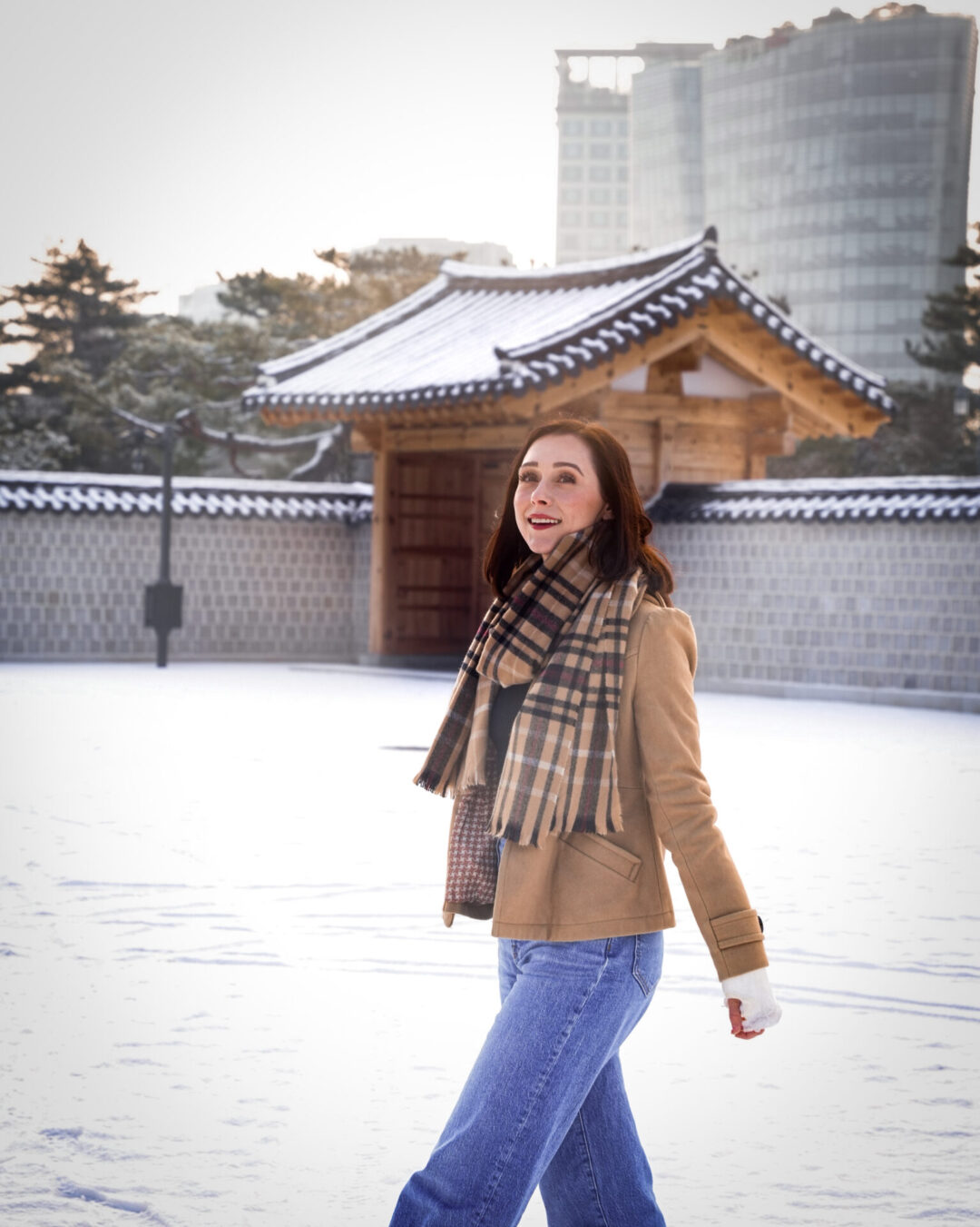 Travel Blogger Jordan Gassner smiling while walking around the snowy courtyard outside of Gyejodang hall In Seoul, South Korea
