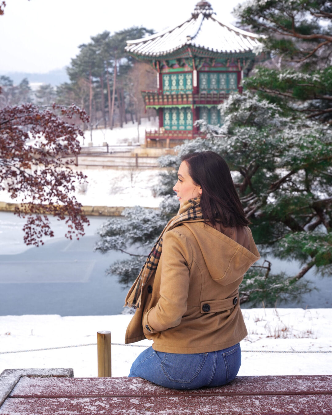 Travel Blogger Jordan Gassner sitting on a bench near a freshly snowed Hyangwonjeong Pavilion inside Gyeongbokgung Palace in Seoul, South Korea