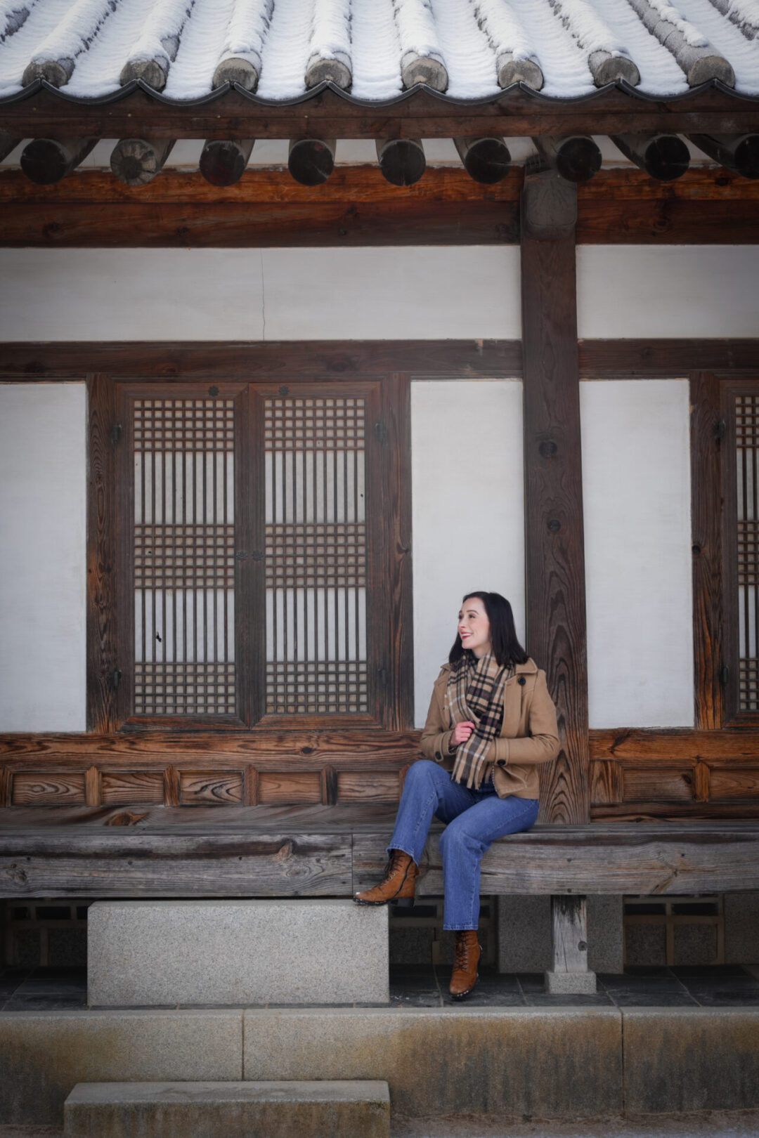 Travel Blogger Jordan Gassner sitting and smiling on a wood platform at Gyeongbokgung Palace in Seoul, South Korea