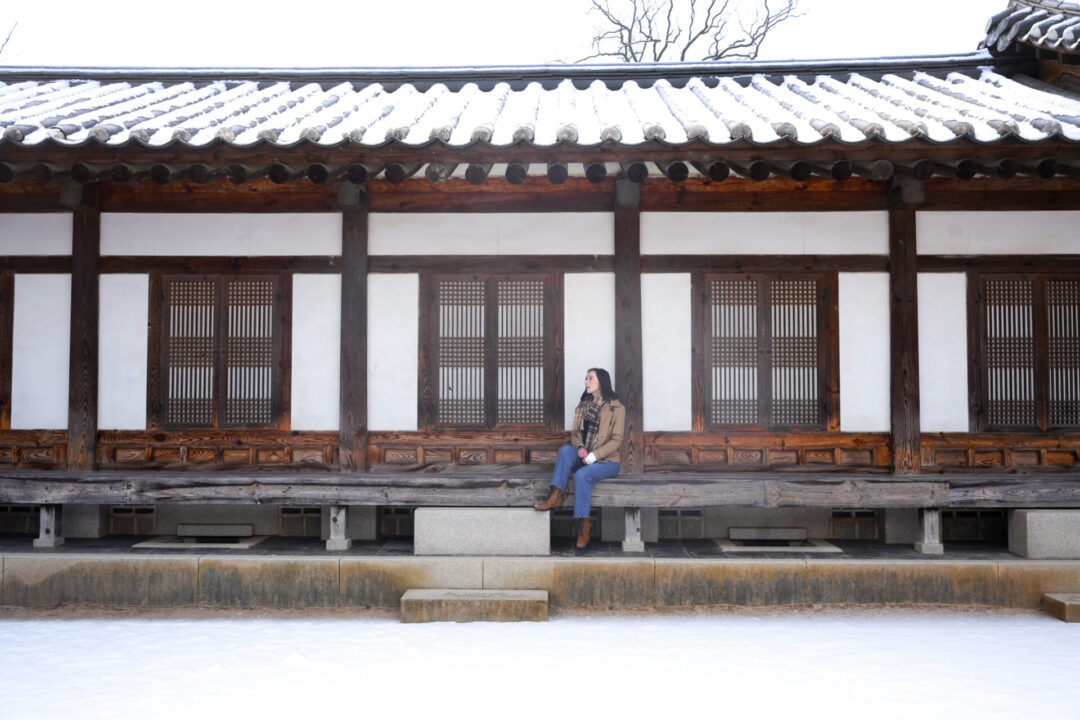 Travel Blogger Jordan Gassner sitting on the porch of Heungbokjeon Hall in Gyeongbokgung Palace in Seoul, South Korea