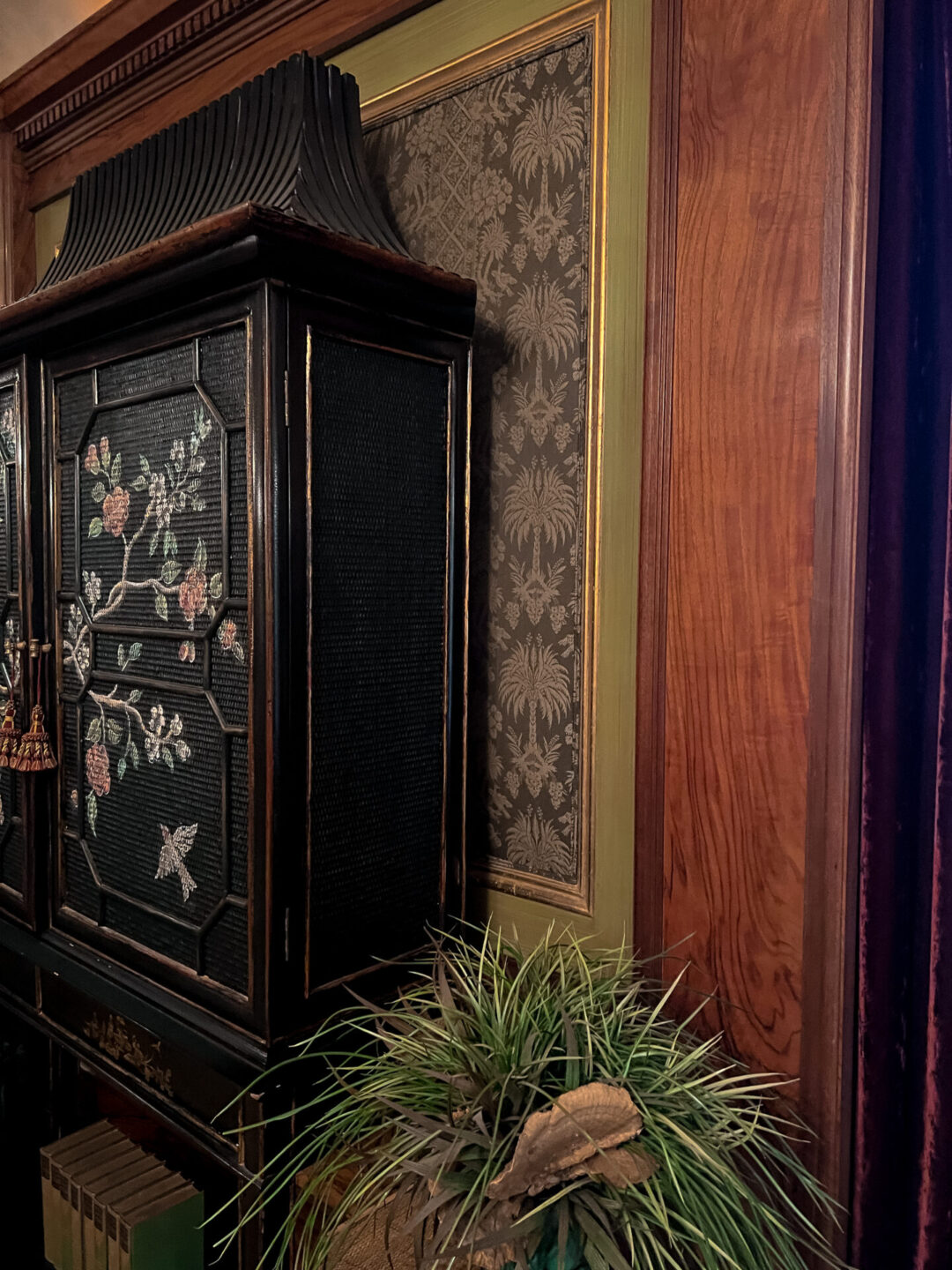 A vintage black cabinet with a floral and bird motif painted along the front inside the Wrigley Mansion in Pasadena, California