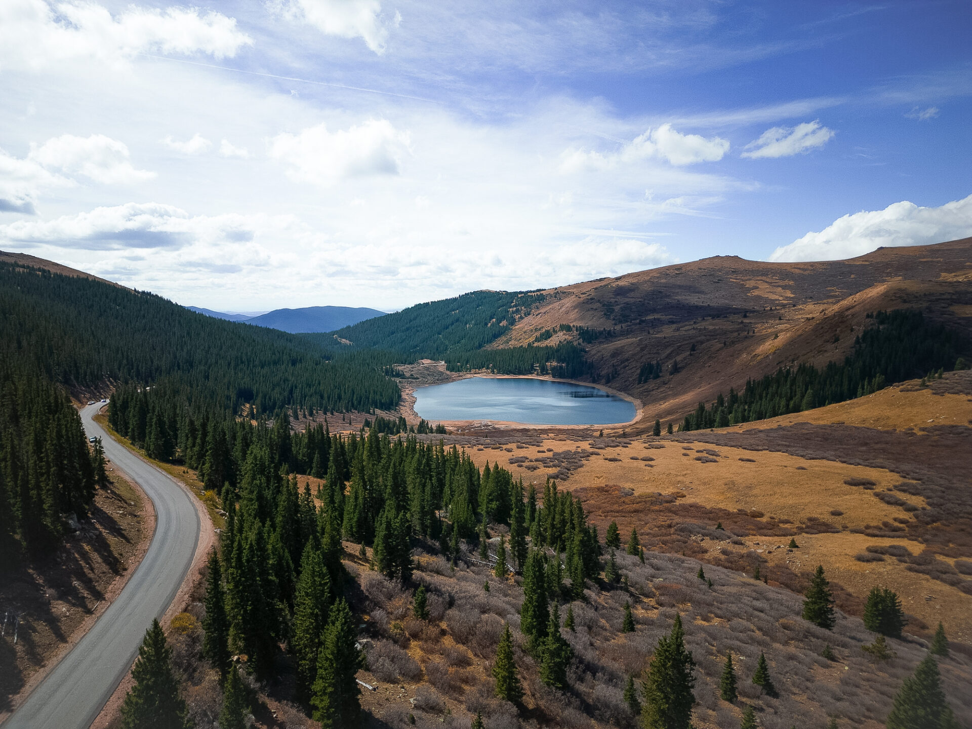 A road along a forested hillside near a lake in Guanella Pass near Georgetown, Colorado