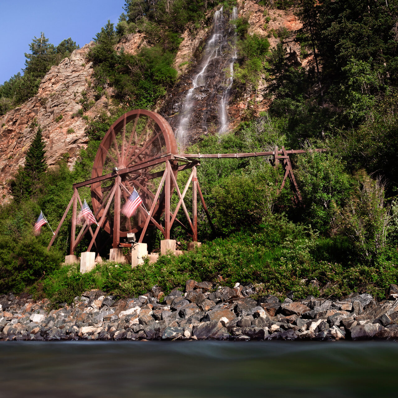 A water wheel decorated with three American Flags in Idaho Springs, Colorado.