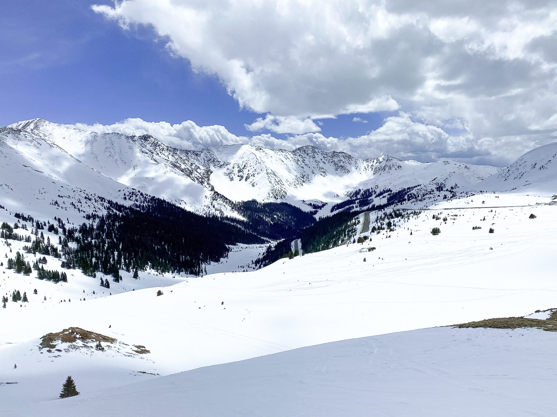 Some clouds in the sky and the sunlight over the snow at Loveland Ski Area near Georgetown, Colorado