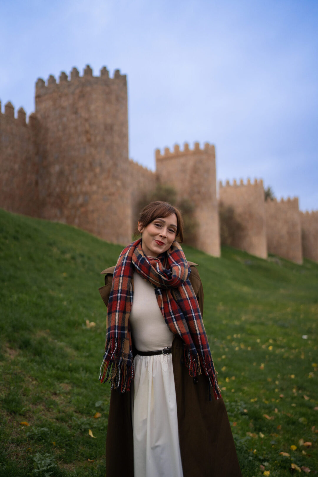 Travel Blogger Jordan Gassner smiling in front of la Muralla de Avila, the medieval wall surrounding the city of Avila, a day trip from Madrid, Spain