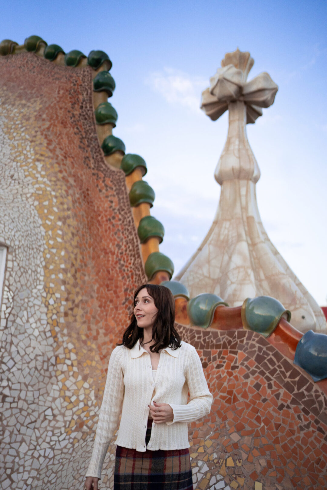 Travel Blogger Jordan Gassner looking over her shoulder along the mosaic rooftop of Casa Batllo in Barcelona, Spain