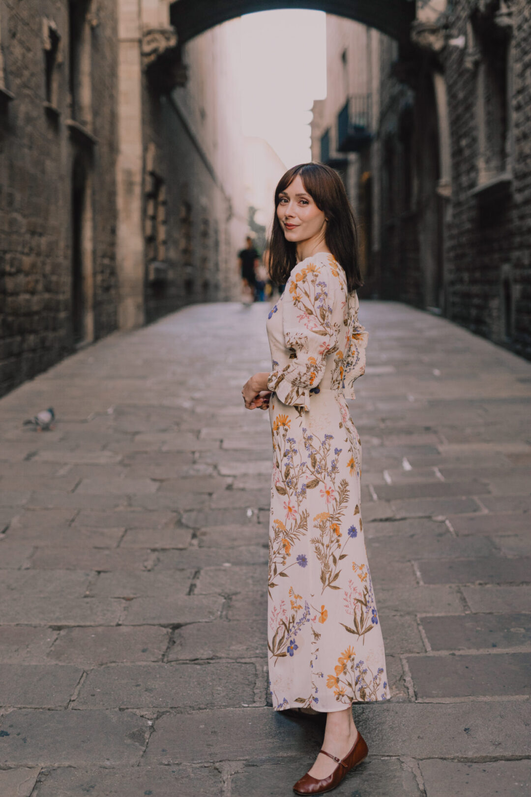 Travel Blogger Jordan Gassner looking over her shoulder while standing underneath Pont del Bisbe in Barcelona, Spain