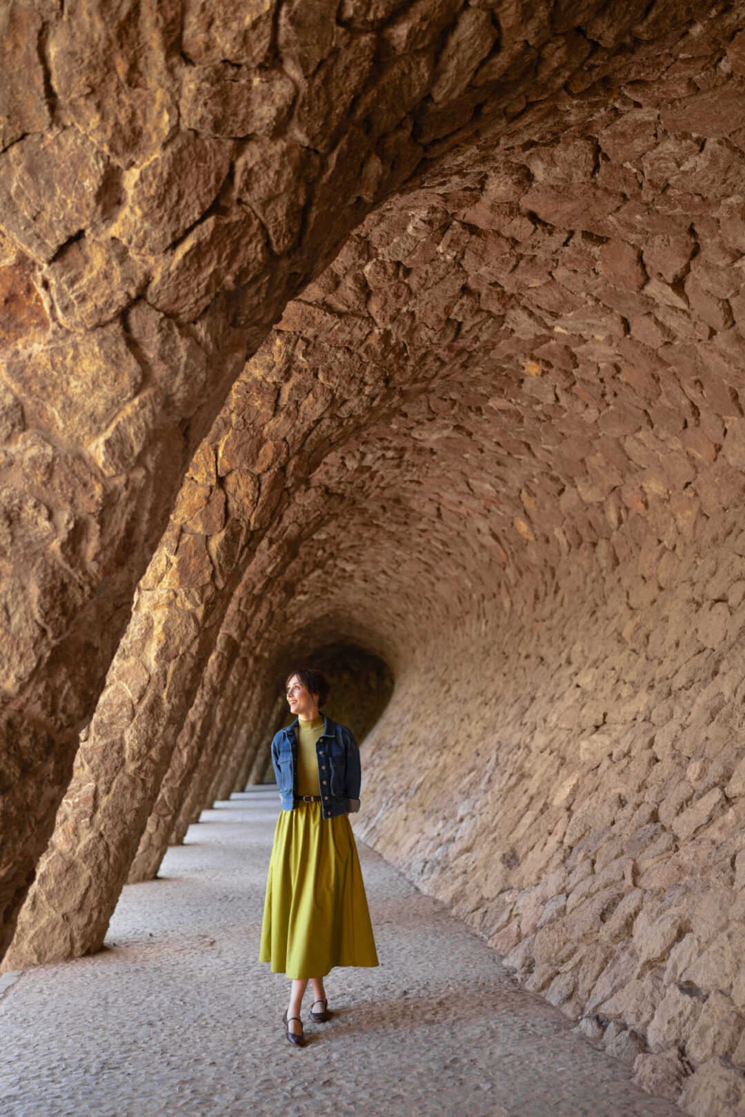 Travel Blogger Jordan Gassner smiling while walking underneath one of Gaudi's epic colonnades inside Park Guell in Barcelona, Spain