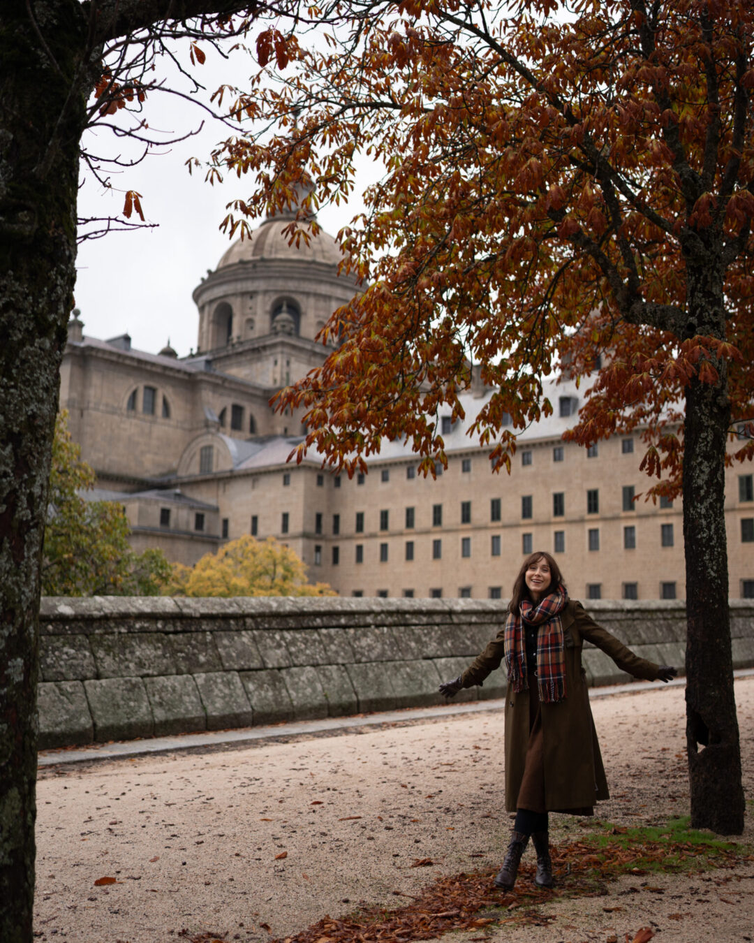 Travel Blogger Jordan Gassner frolicking in the fall foliage outside the Royal Site of El Escorial in Spain