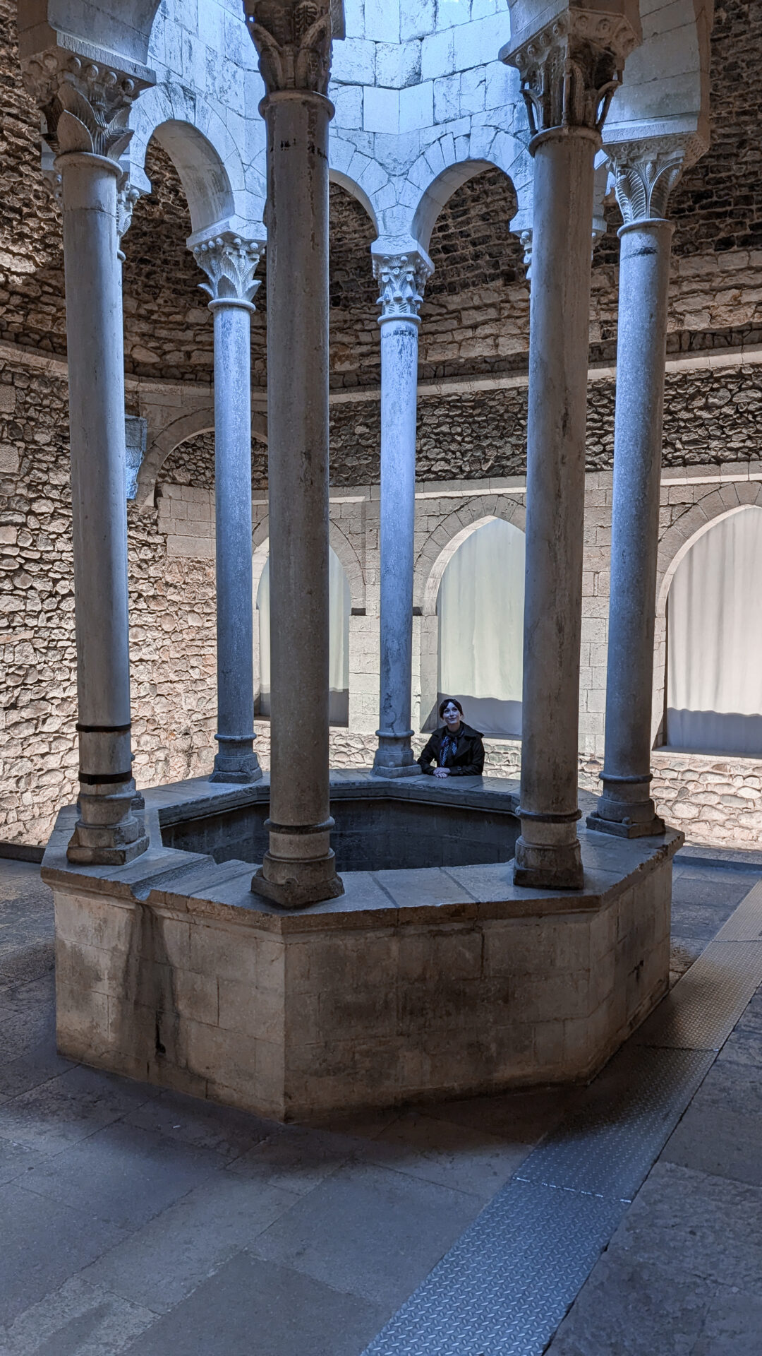 Travel Blogger Jordan Gassner standing at the edge of a well inside the Arab Baths, a Game of Thrones filming location in Spain