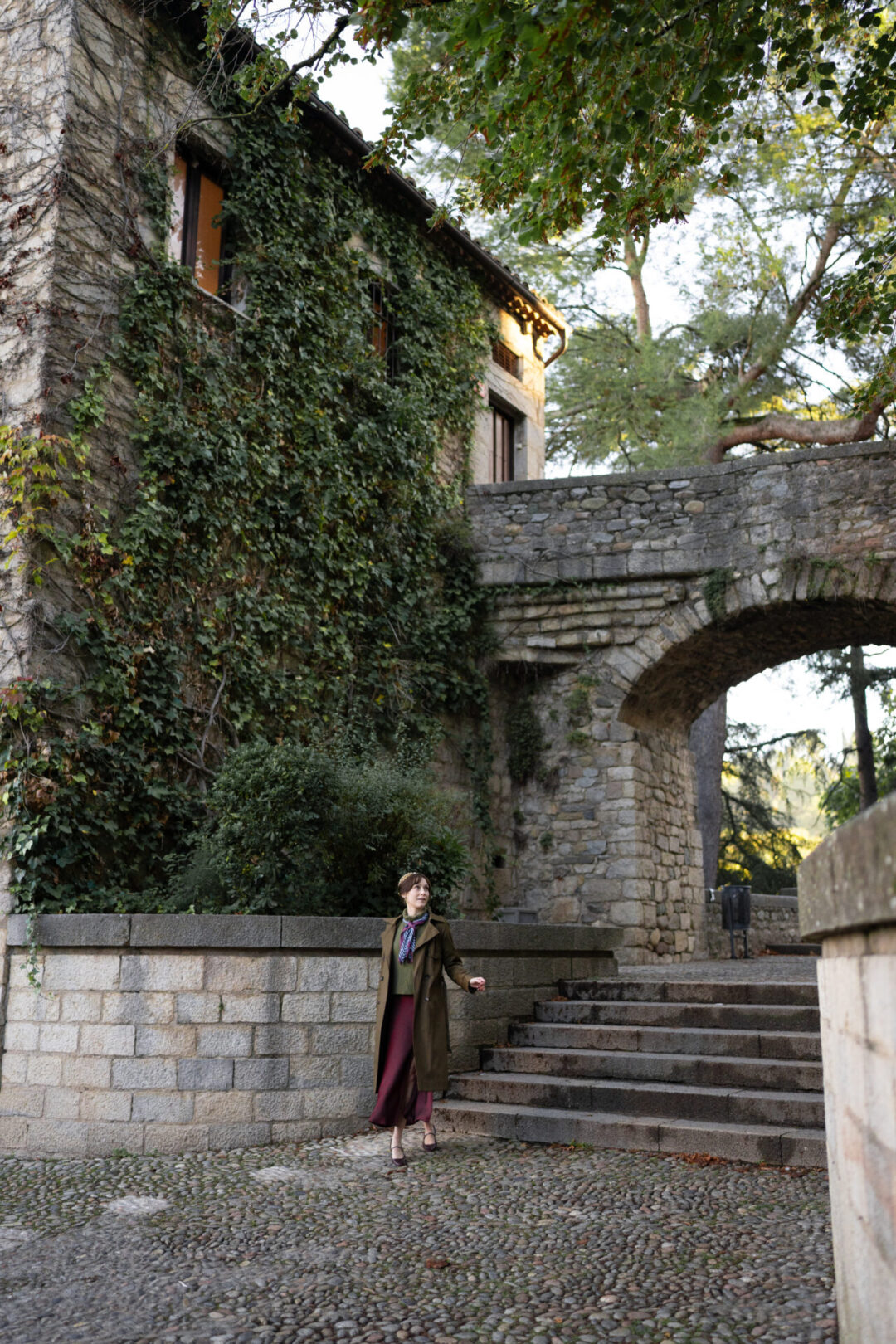 Travel Blogger Jordan Gassner walking away from an archway and set of stairs in Girona, Spain