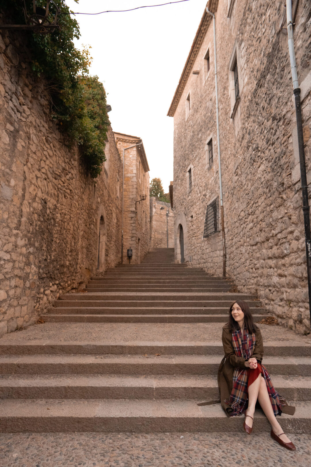 Travel Blogger Jordan Gassner smiling from the steps of Bisbe Josep Cartana Street in Girona, Spain