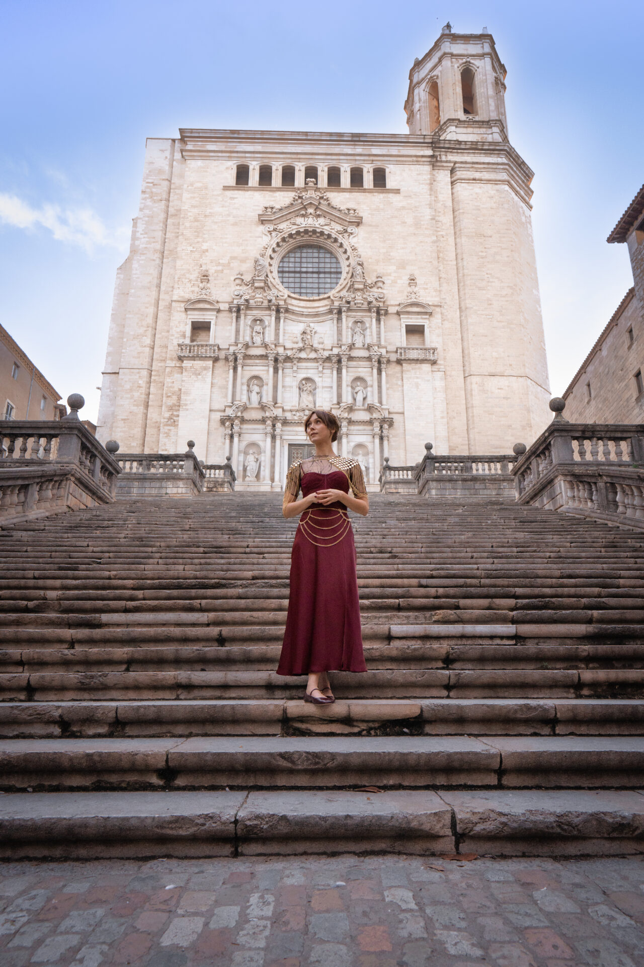 Travel Blogger Jordan Gassner wearing a medieval inspired dress and chainmail on the steps of Girona Cathedral in Catalonia, Spain just north of Barcelona